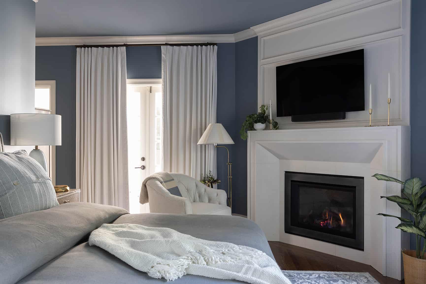 Close-up view of bedroom with blue paint and a fire burning in the fireplace.
