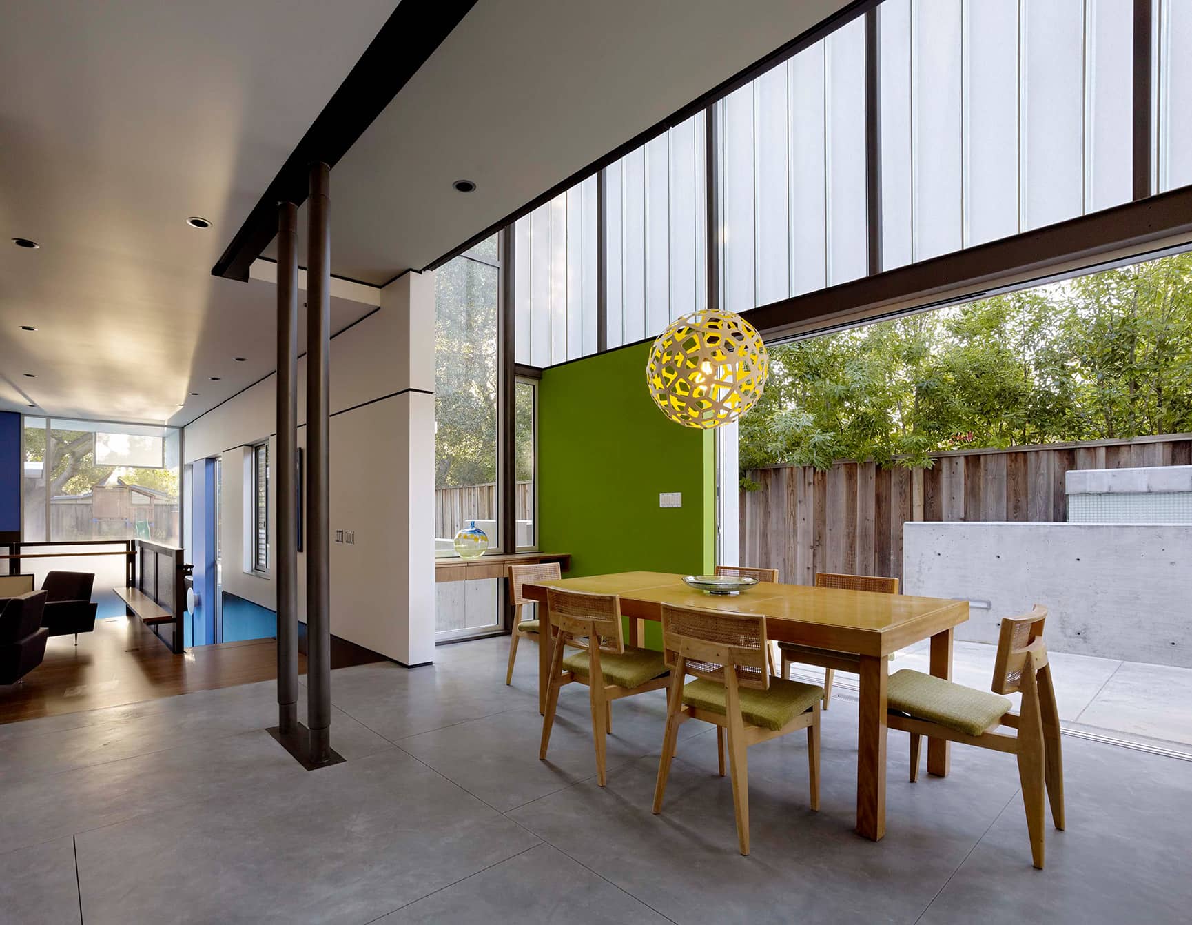 Mid-century modern home with high ceilings and dining area near large open doors.