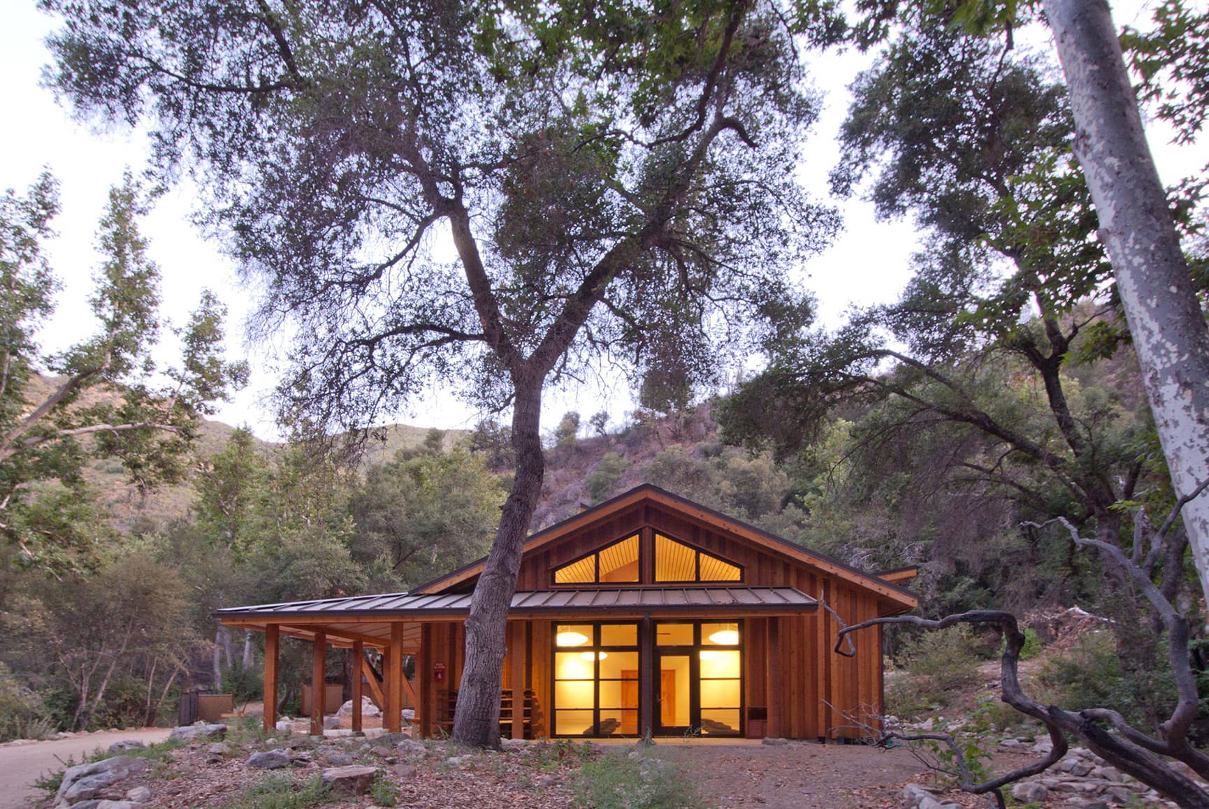 Exterior side view of newly constructed building used as a yoga retreat nestled in the woods.