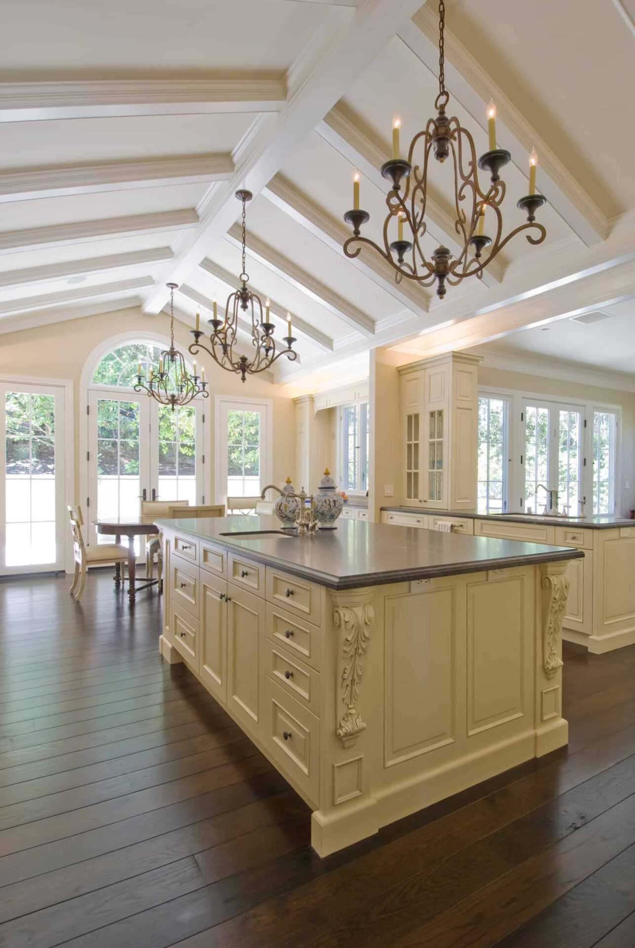 Ornate kitchen with large island and dark wood floors.